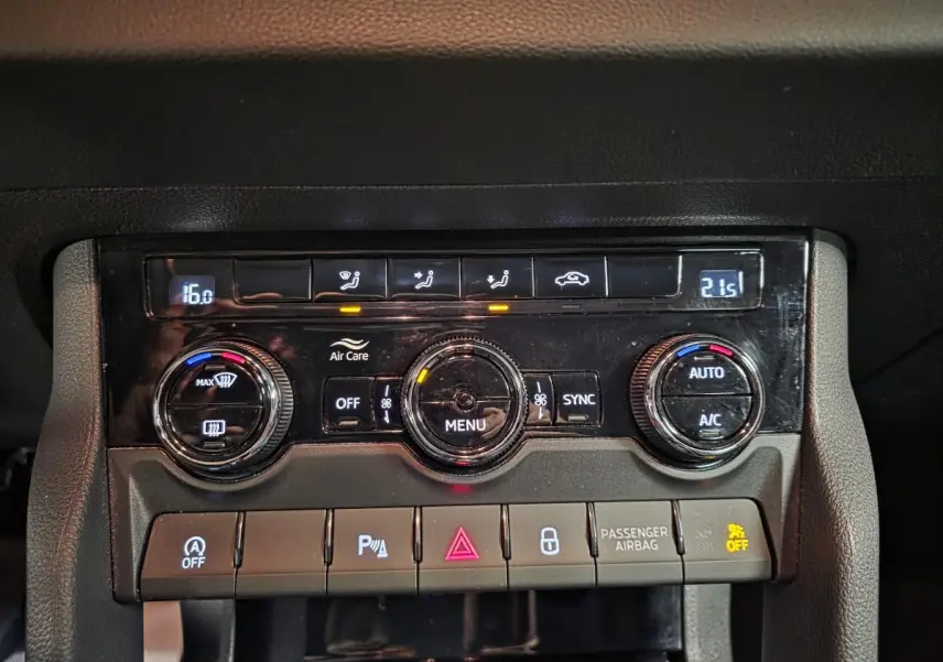 Gros plan sur la console centrale du Skoda Karoq 2024 avec commandes climatisation digitale et boutons fonctionnels.
