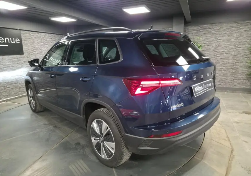 Vue 3/4 arrière droite d’un Skoda Karoq bleu métallisé avec feux arrière LED et jantes alliage 17 pouces.