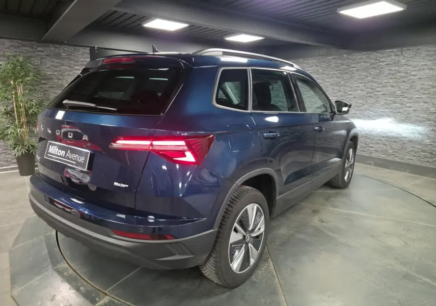 Vue 3/4 arrière droite d'un Skoda Karoq bleu métallisé 2024 avec feux arrière LED et jantes alliage 17 pouces.