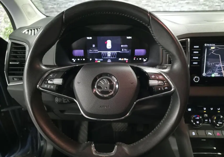 Vue frontale du volant cuir noir du Skoda Karoq 2024 avec tableau de bord digital et écran tactile de navigation.