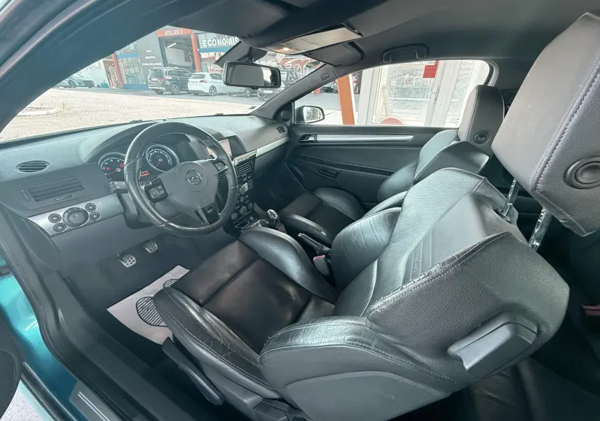 Intérieur noir cuir de l'Opel Astra OPC 2008, vue côté conducteur avec volant et sièges sport visibles.