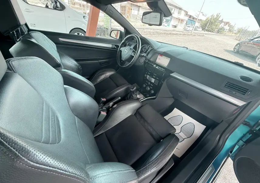 Vue intérieure côté conducteur de l'Opel Astra OPC 2008 avec sièges sport en cuir noir et tableau de bord moderne.