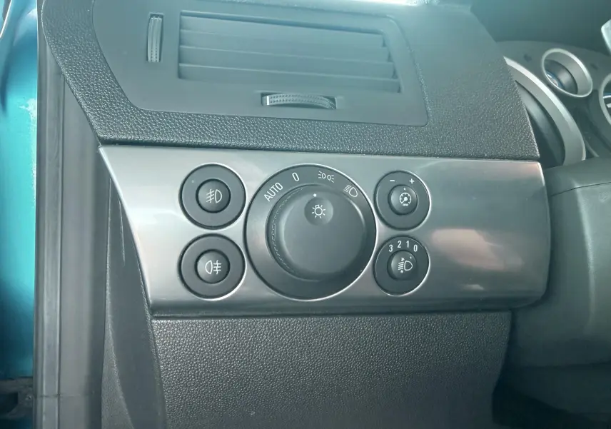 Détail du tableau de bord côté gauche avec commandes d’éclairage sur Opel Astra OPC bleu 2008.