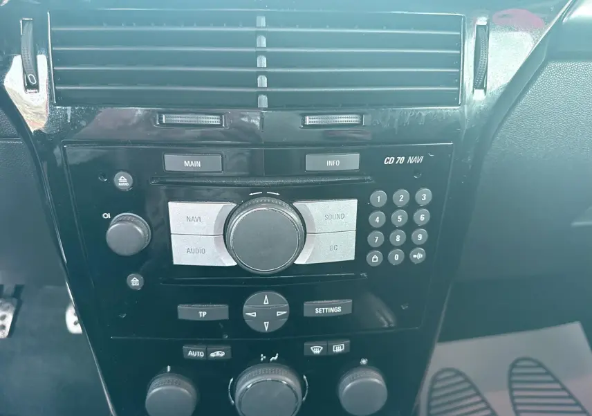 Gros plan sur la console centrale noire de l’Opel Astra OPC 2008 avec commandes audio et climatisation.