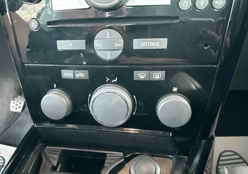 Gros plan sur la console centrale noire de l’Opel Astra OPC 2008, montrant les commandes de climatisation et audio.