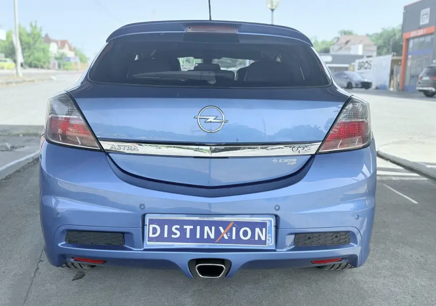 Vue arrière d'une Opel Astra OPC bleue de 2008 avec échappement central et feux arrière fumés.