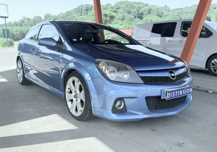 Opel Astra OPC bleu vue 3/4 avant droit sous abri avec jantes alliage et calandre noire.