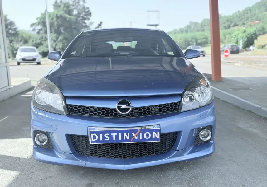 Vue avant d'une Opel Astra OPC bleue 2008 avec calandre noire et phares doubles sous abri.