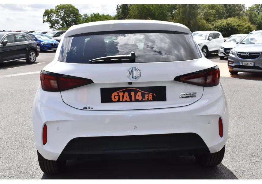 Vue arrière d'une MG3 1.5 HYBRID+ 195 LUXURY blanche de 2026 avec feux arrière sombres et logo MG central.