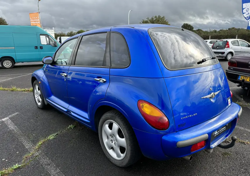 Vue 3/4 arrière droite d'une Chrysler PT Cruiser 2.2L CRD GO bleu de 2004 avec attelage et vitres teintées.