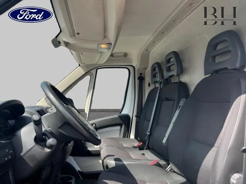 Intérieur côté conducteur du Citroën Jumper blanc, montrant les sièges avant en tissu gris et le volant multifonction.