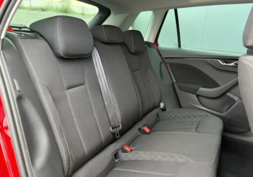 Vue intérieure du siège arrière côté droit d'une Skoda Kamiq rouge Velvet, avec sellerie tissu noire et surpiqûres grises.