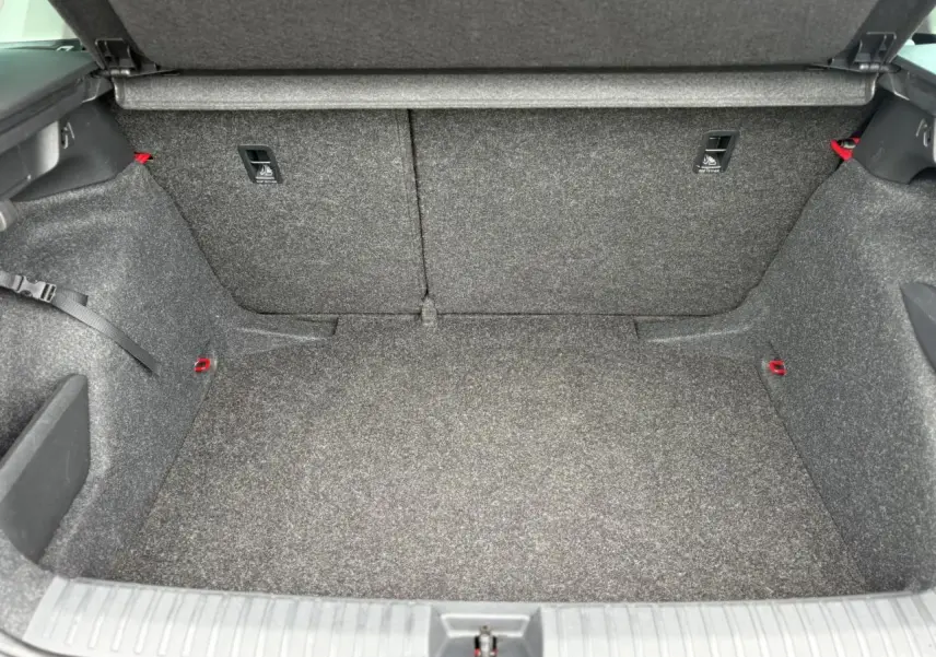 Coffre ouvert du Skoda Kamiq 2024, vue intérieure montrant le revêtement gris et les fixations ISOFIX rouges.