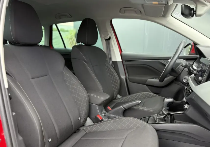 Vue intérieure côté conducteur du Skoda Kamiq rouge Velvet 2024, sièges noirs avec coutures contrastées et volant multifonctions.