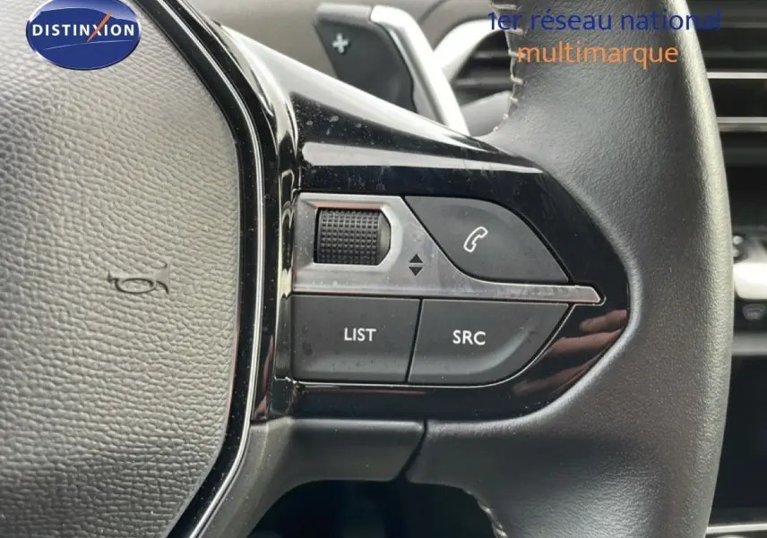 Gros plan sur les commandes gauche du volant cuir noir du Peugeot 3008 1.6 Hybrid 2024, boutons LIST et SRC visibles.