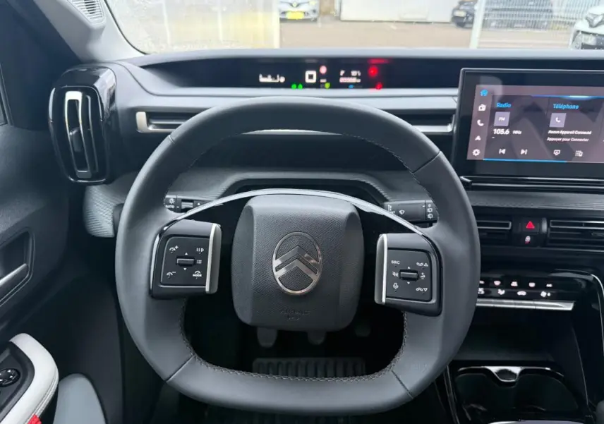 Vue intérieure centrée sur le volant de la Citroën C3 2025, avec tableau de bord numérique et écran tactile.