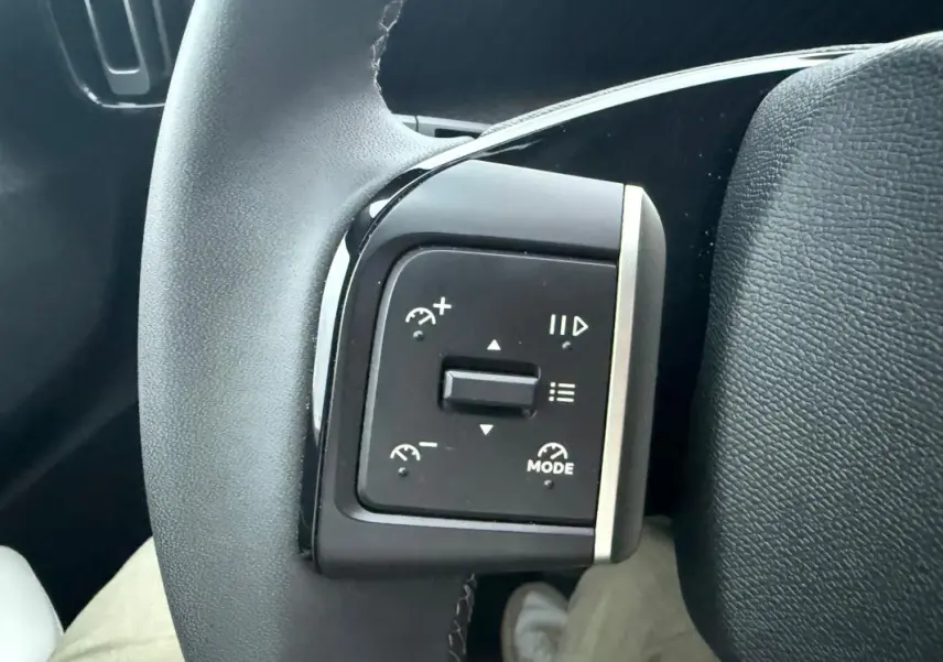 Gros plan sur les commandes de régulateur de vitesse au volant noir d'une Citroën C3 gris 2025.