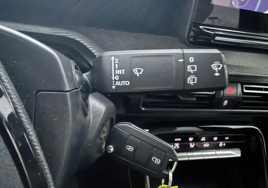 Gros plan sur la commande des essuie-glaces et la clé dans le contact d’une Citroën C3 gris, tableau de bord en arrière-plan.