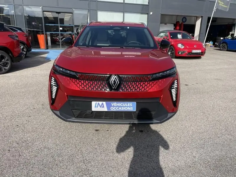Vue de face du Renault Scénic E-Tech électrique rouge flamme 2024, avec calandre à motif hexagonal et feux LED verticaux.