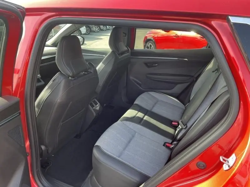 Vue intérieure côté gauche sur l'arrière du Renault Scénic E-Tech électrique rouge flamme, montrant les sièges arrière et les finitions tissu et cuir.