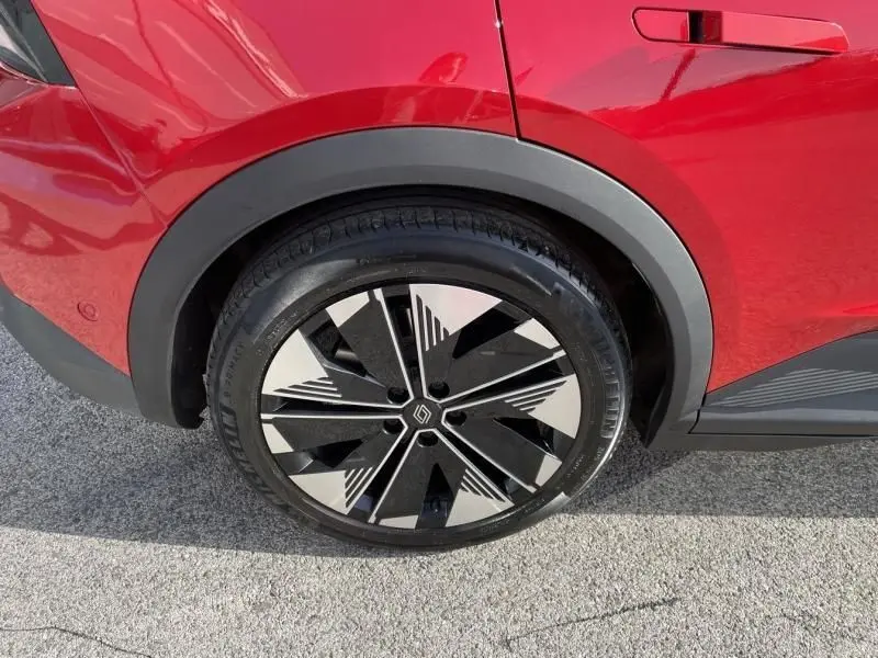 Gros plan sur la roue arrière droite du Renault Scénic E-Tech Rouge Flamme 2024 avec jante au design géométrique noir et argent.