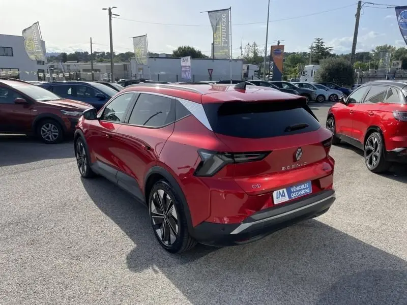 Vue 3/4 arrière droite d’un Renault Scénic E-Tech électrique 2024 rouge flamme avec jantes noires et vitres teintées.