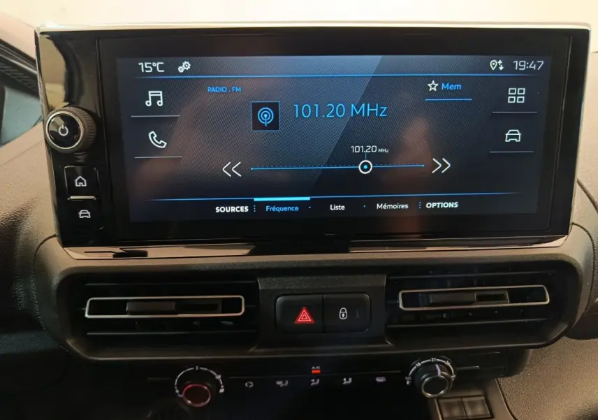 Gros plan sur l’écran tactile central du Peugeot Partner 2025 affichant la radio FM à 101,20 MHz, avec commandes et aérateurs.