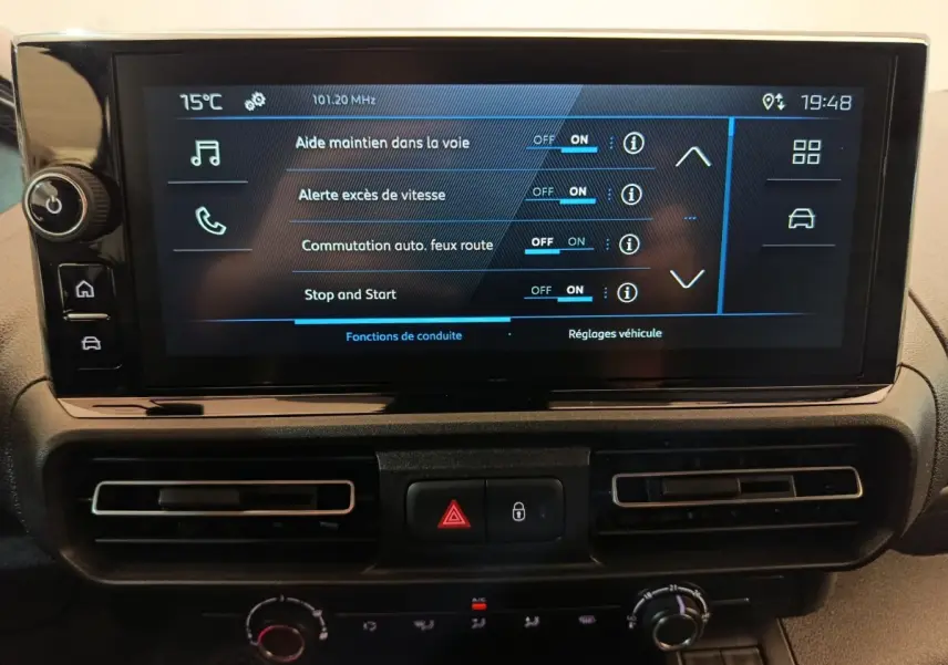 Écran tactile central du Peugeot Partner 2025 affichant les réglages d’aides à la conduite, avec commandes et aérateurs en dessous.