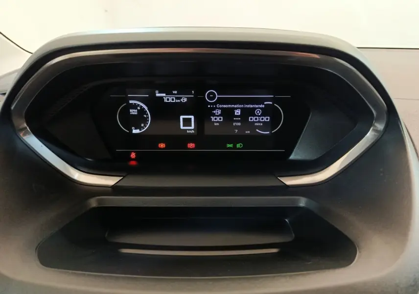 Vue rapprochée du tableau de bord numérique du Peugeot Partner 2025, affichant la consommation instantanée et les alertes.