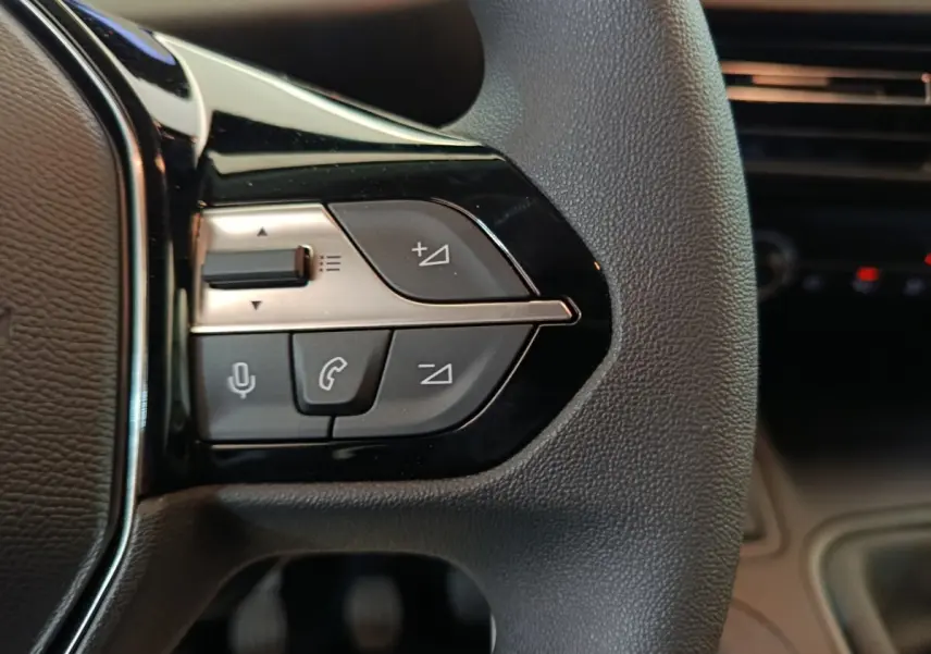 Gros plan sur les commandes multifonctions à gauche du volant du Peugeot Partner 2025, intérieur noir.