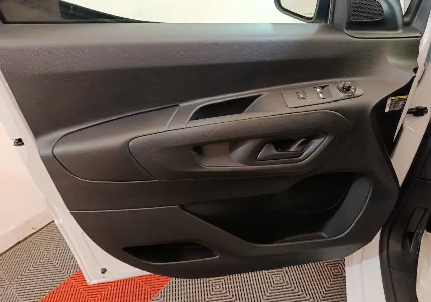 Vue rapprochée de la porte avant gauche blanche du Peugeot Partner 2025, avec commandes électriques et poignée noire.