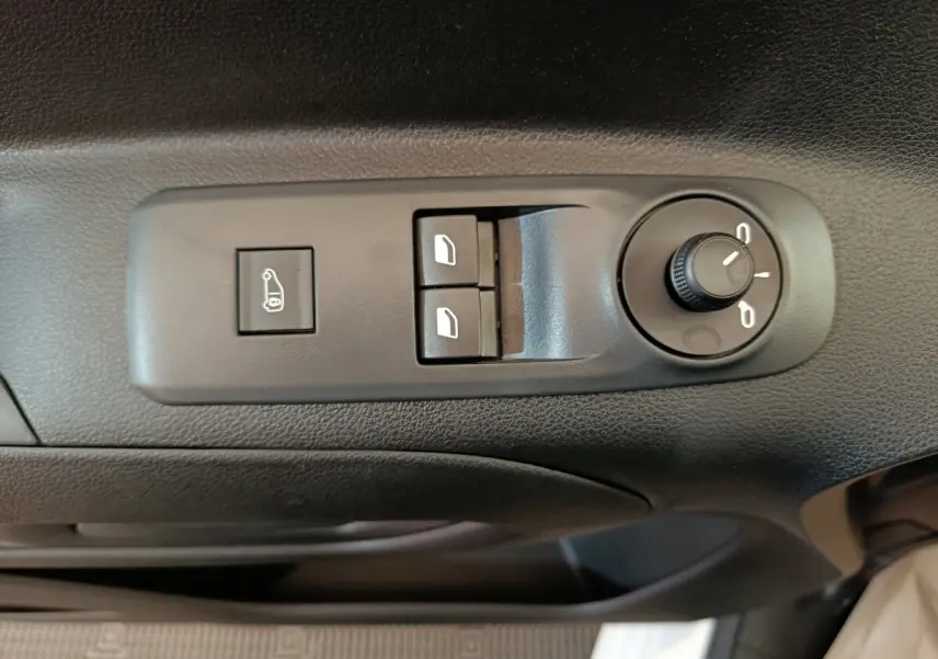 Vue rapprochée des commandes de réglage des rétroviseurs et des vitres sur la porte côté conducteur d’un Peugeot Partner blanc.