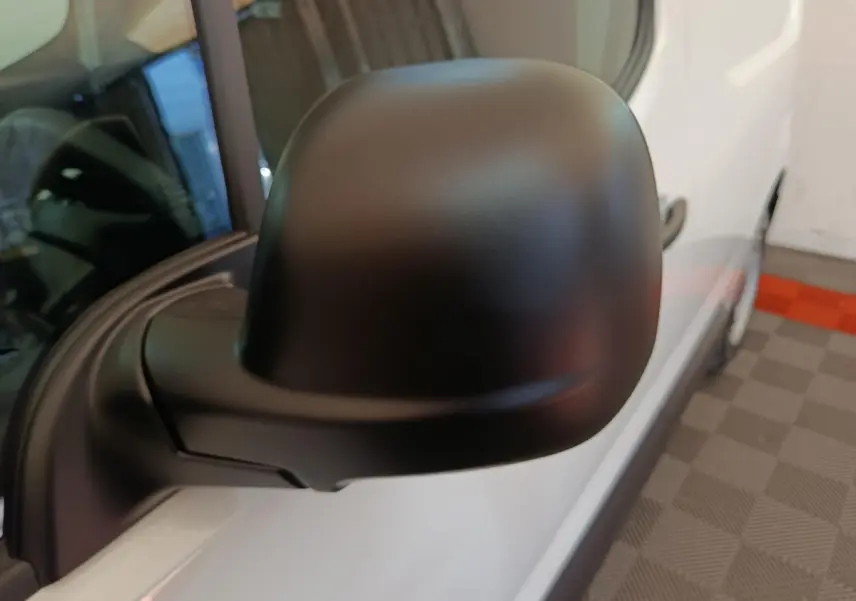 Rétroviseur noir en gros plan côté gauche du Peugeot Partner blanc, vue rapprochée sur porte avant.