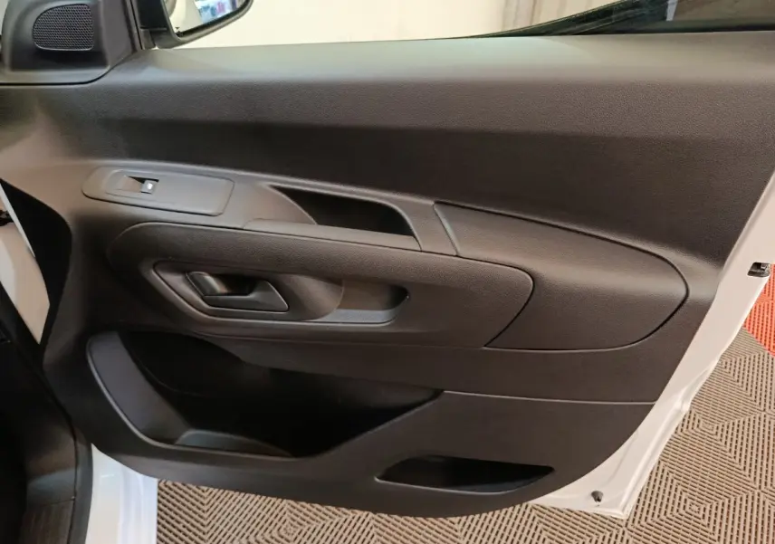 Vue rapprochée de la porte côté conducteur noire du Peugeot Partner blanc, avec poignée et commande de vitre.