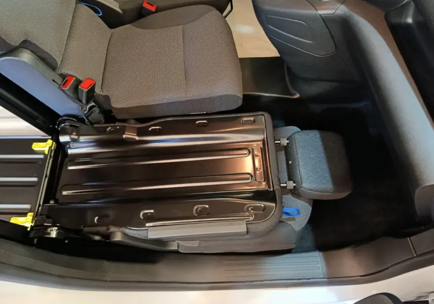Vue intérieure plongeante sur le siège passager relevé du Peugeot Partner blanc, montrant la structure métallique et l'assise grise.