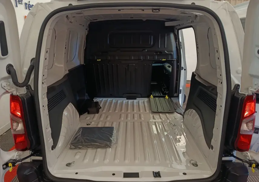 Vue arrière du Peugeot Partner blanc 2025, montrant l'espace de chargement vide avec cloison pleine noire.