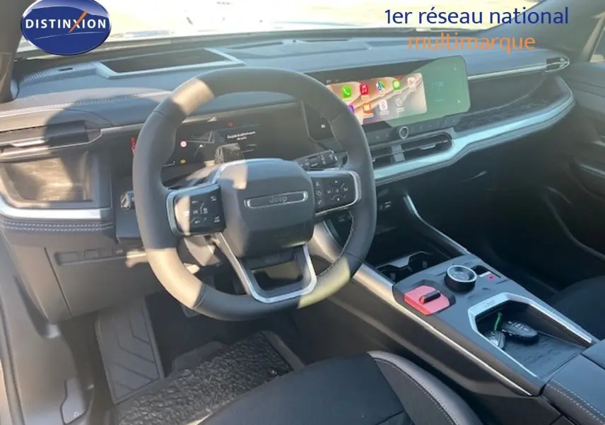 Vue intérieure du poste de conduite du Jeep Compass 2026, tableau de bord et volant multifonction en noir.