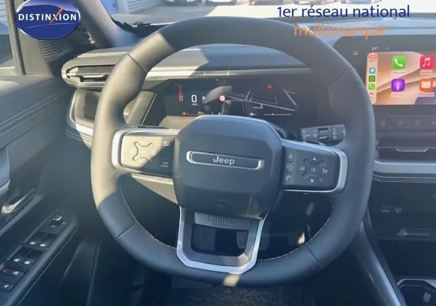 Vue centrée sur le volant Jeep noir du Compass 2026, tableau de bord digital et écran tactile en arrière-plan.