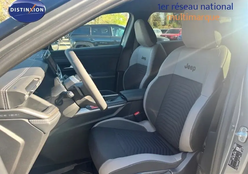 Vue intérieure côté conducteur du Jeep Compass 2026, sièges bi-ton gris clair et noir avec logo Jeep brodé.