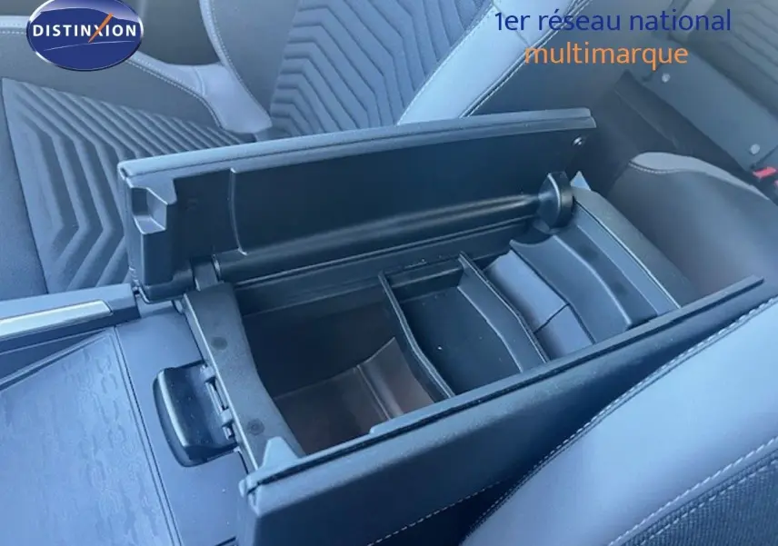 Vue rapprochée de l'accoudoir central ouvert et des sièges en tissu gris à motifs géométriques dans un Jeep Compass 2026.