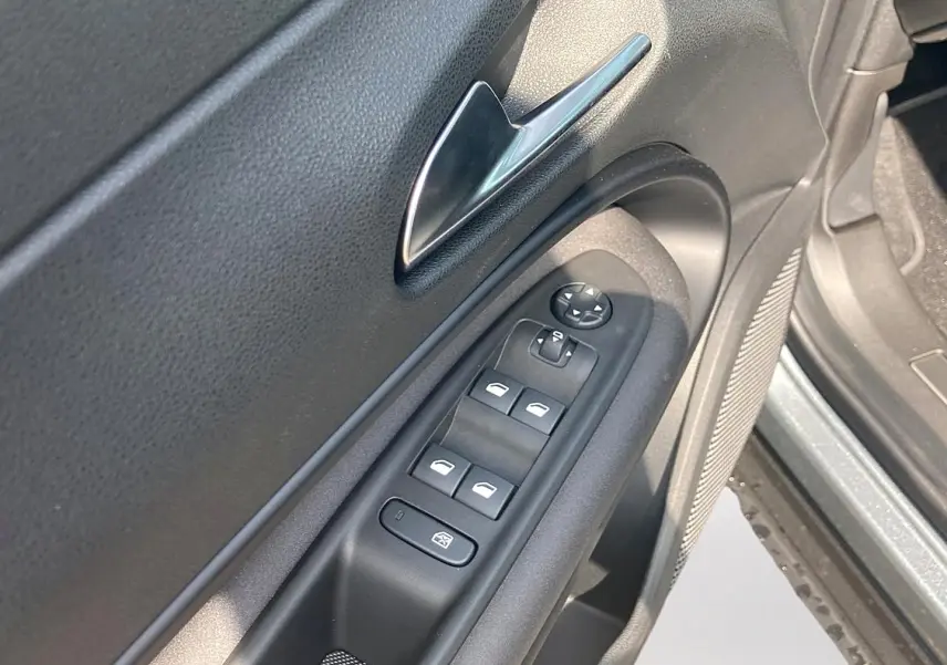 Gros plan sur la porte avant gauche grise de l'Alfa Romeo Junior 1.2 hybride, montrant les commandes des vitres et le bouton de verrouillage.