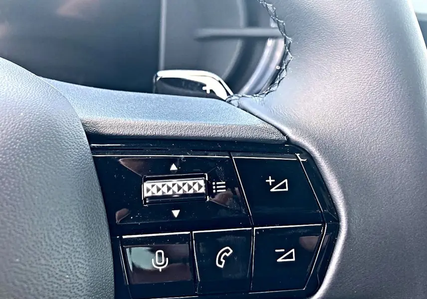 Gros plan sur les commandes noires au volant de l'Alfa Romeo Junior gris, mettant en valeur les boutons de volume et de téléphone.