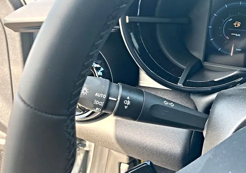 Gros plan sur le commodo gauche derrière le volant noir de l'Alfa Romeo Junior gris, avec tableau de bord partiellement visible.