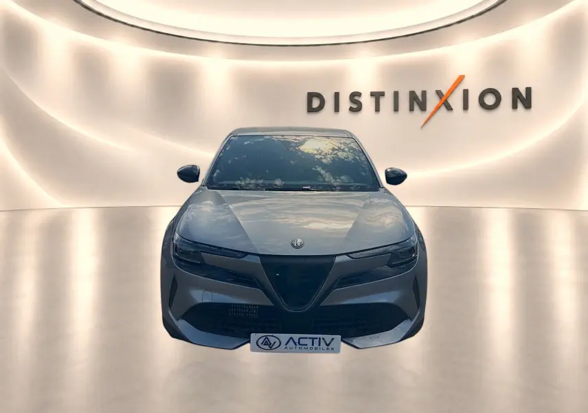 Vue frontale d'une Alfa Romeo Junior 1.2 hybride grise, avec calandre caractéristique et phares LED matrix allumés.