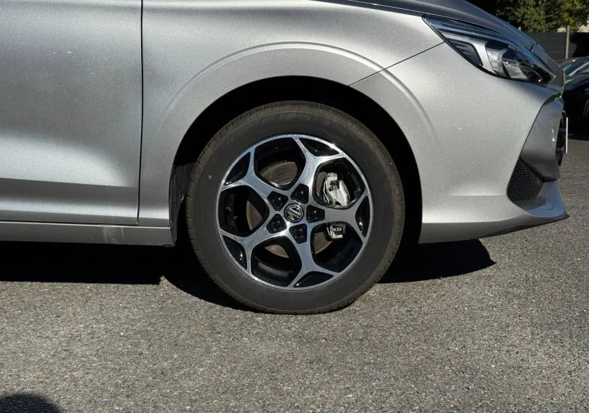 Gros plan sur la roue avant gauche et partie avant d'une MG3 Cosmic Silver métallisé avec jante alu noire et argent.