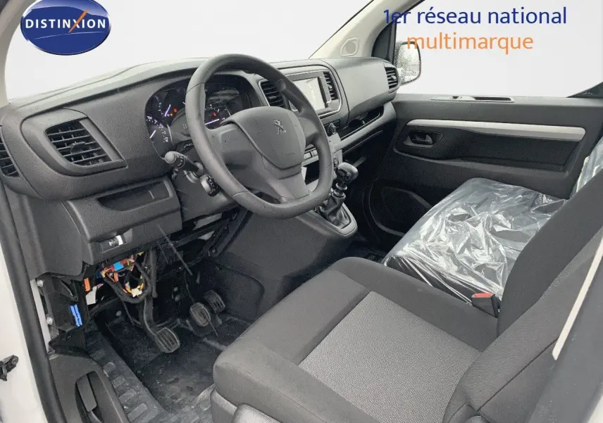 Vue intérieure côté conducteur du Peugeot Expert Long 2023, montrant le tableau de bord et siège noir avec plastique protecteur.