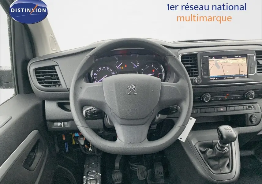 Vue intérieure centrée sur le volant Peugeot et la console avec levier de vitesses manuelle, tableau de bord et écran GPS visibles.