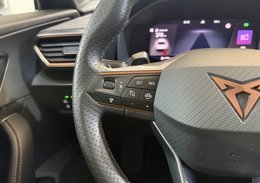 Gros plan sur le volant cuir perforé noir avec commandes multifonctions et logo CUPRA cuivré du Formentor 2023.