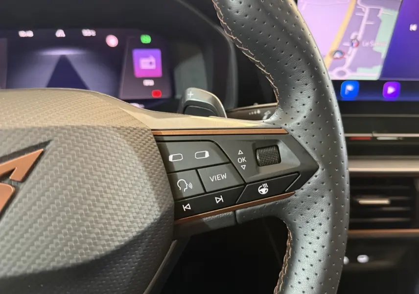 Gros plan sur le volant en cuir perforé noir du CUPRA Formentor 2023 avec commandes multifonctions et tableau de bord numérique.