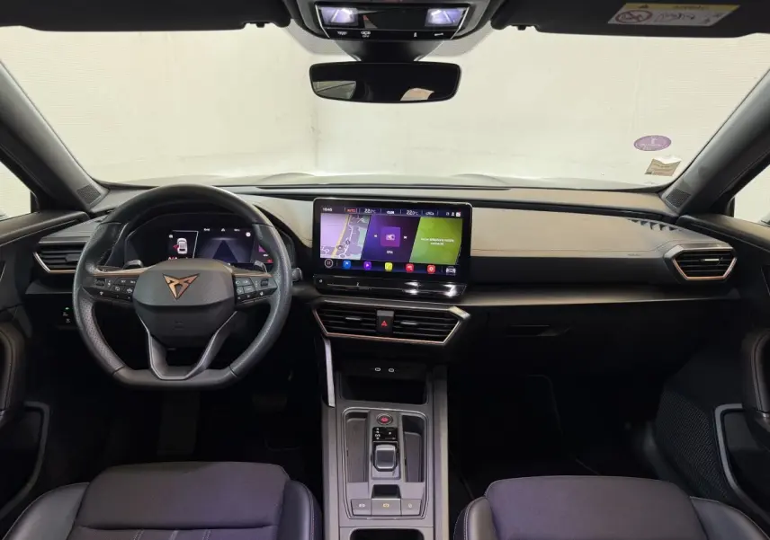 Intérieur noir du CUPRA Formentor 1.5 TSI 2023 vu de face, tableau de bord moderne avec écran tactile central lumineux.